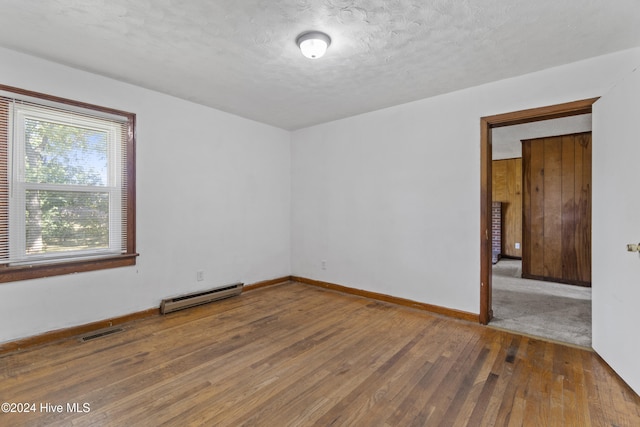 spare room with hardwood / wood-style flooring, a textured ceiling, and baseboard heating