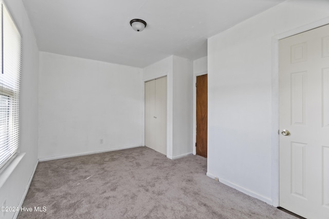 unfurnished bedroom featuring light colored carpet and a closet