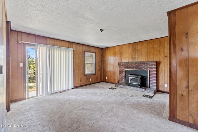 unfurnished living room with plenty of natural light, light carpet, and a wood stove