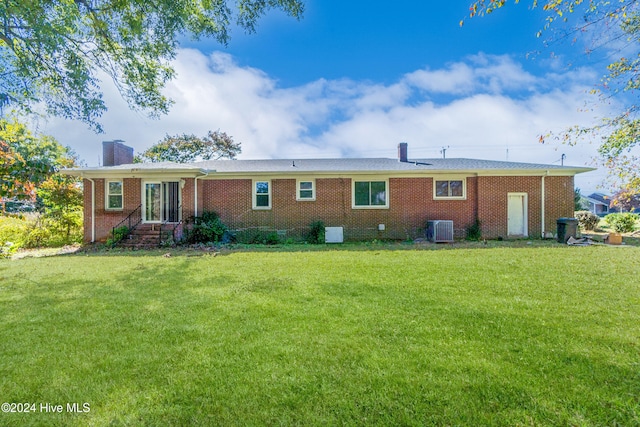 rear view of property with central AC unit and a yard