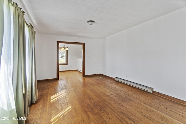 spare room featuring hardwood / wood-style flooring and a baseboard heating unit