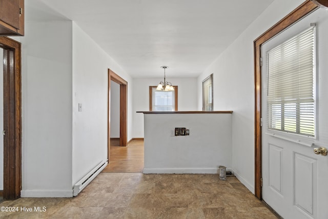 spare room with a baseboard heating unit, plenty of natural light, and a chandelier