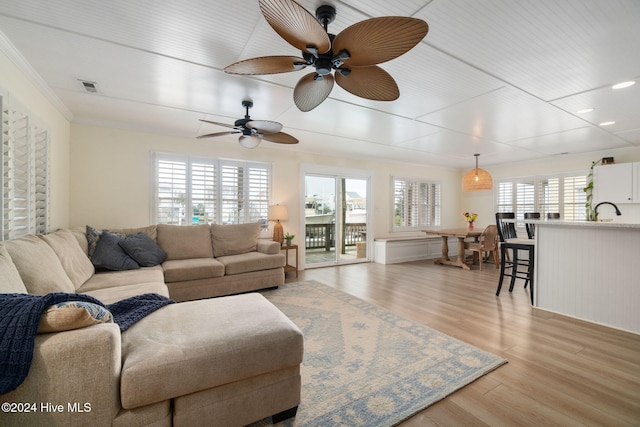 living room featuring crown molding, ceiling fan, and light hardwood / wood-style flooring