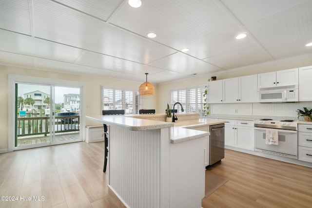 kitchen featuring pendant lighting, white cabinetry, sink, a kitchen island with sink, and white appliances