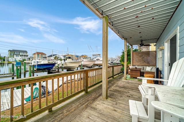 wooden deck with a water view, outdoor lounge area, and a boat dock