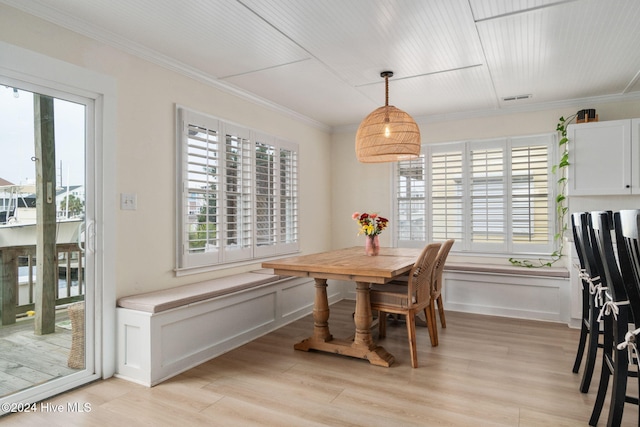 dining space with ornamental molding and light hardwood / wood-style floors