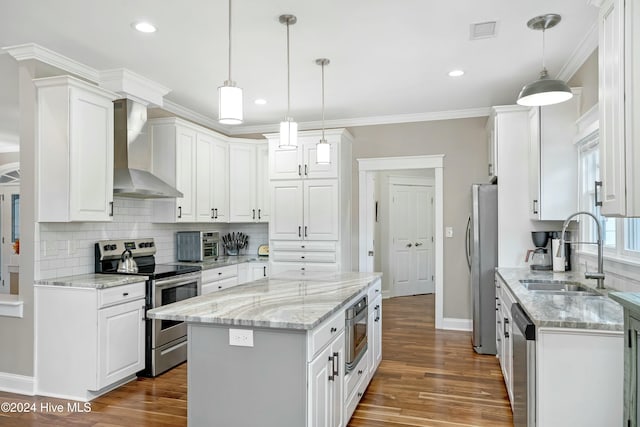 kitchen featuring white cabinets, a center island, wall chimney exhaust hood, and stainless steel appliances