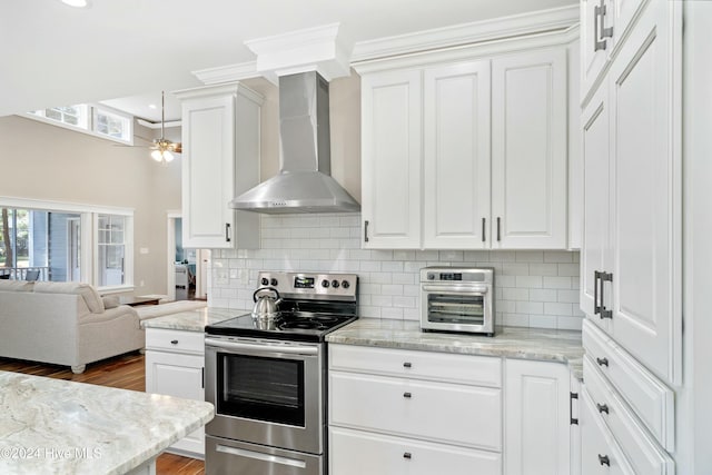 kitchen featuring dark hardwood / wood-style flooring, ceiling fan, wall chimney range hood, electric range, and white cabinets