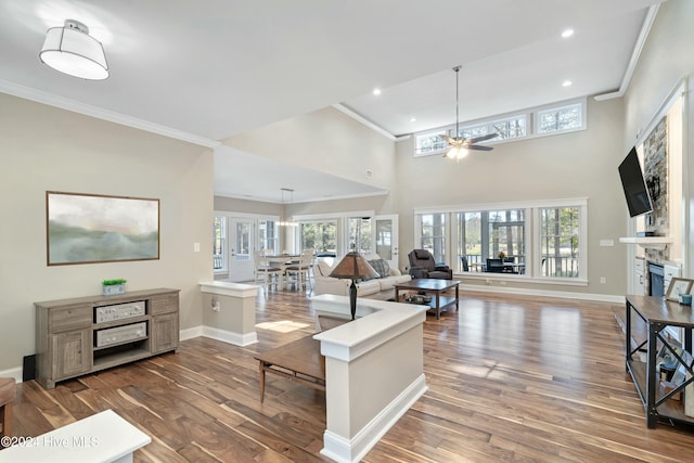 living room with ceiling fan, dark hardwood / wood-style flooring, a towering ceiling, and crown molding