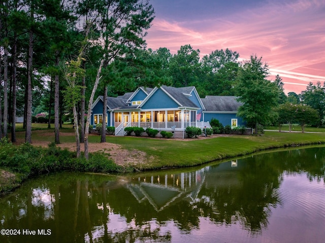 view of front of home with a yard, a water view, and a porch