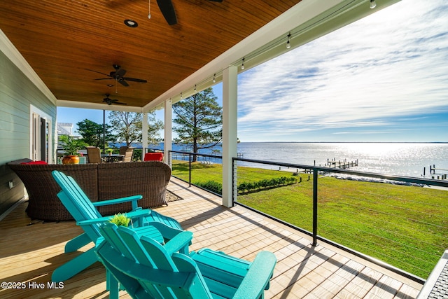 deck with a water view, ceiling fan, and a yard