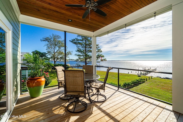wooden deck featuring a ceiling fan, outdoor dining space, a water view, and a yard