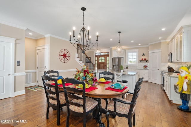 dining room with wood-type flooring, recessed lighting, crown molding, and stairs