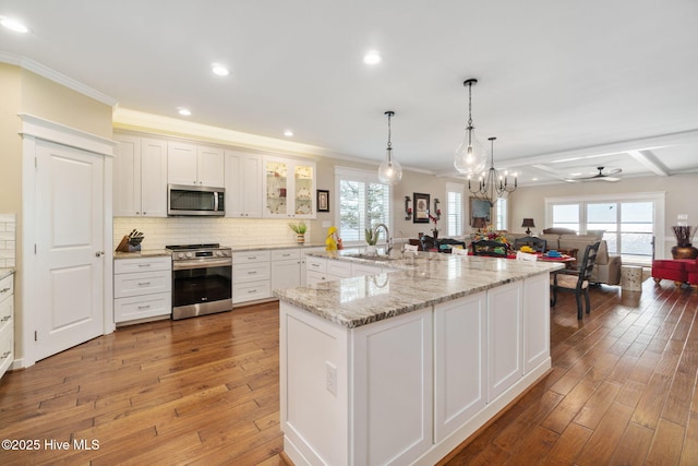 kitchen featuring ornamental molding, open floor plan, light wood-type flooring, a sink, and stainless steel appliances
