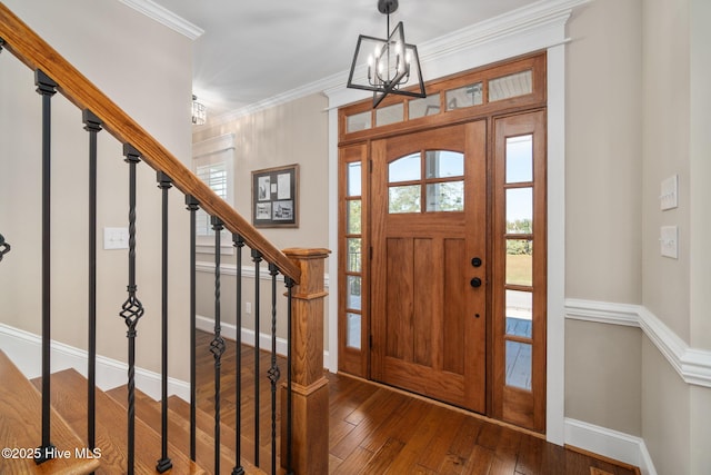 entryway with crown molding, an inviting chandelier, hardwood / wood-style floors, baseboards, and stairway