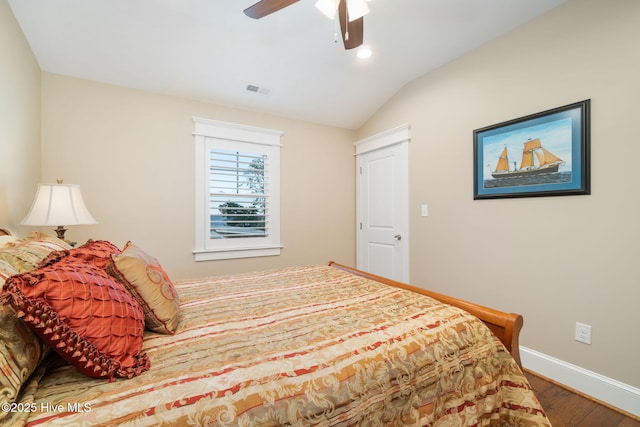 bedroom with ceiling fan, visible vents, vaulted ceiling, wood finished floors, and baseboards