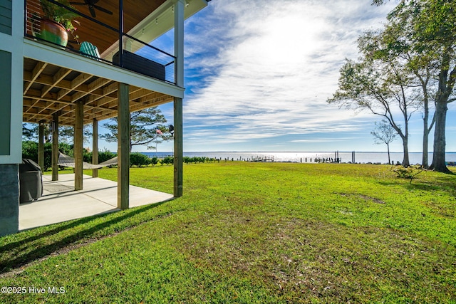 view of yard with a patio, a water view, and a balcony