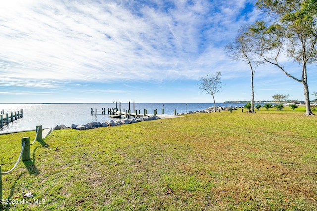 view of dock with a lawn and a water view