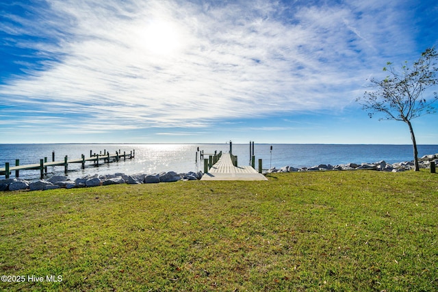 view of dock with a lawn and a water view