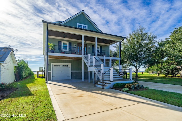 beach home featuring an attached garage, a front lawn, covered porch, and concrete driveway