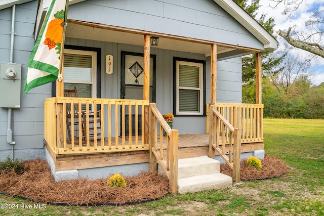 doorway to property with covered porch and a lawn