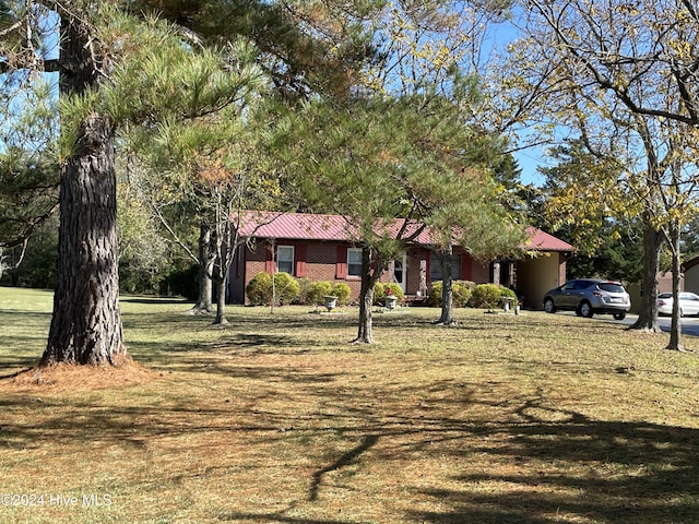 ranch-style home featuring metal roof, brick siding, and a front yard