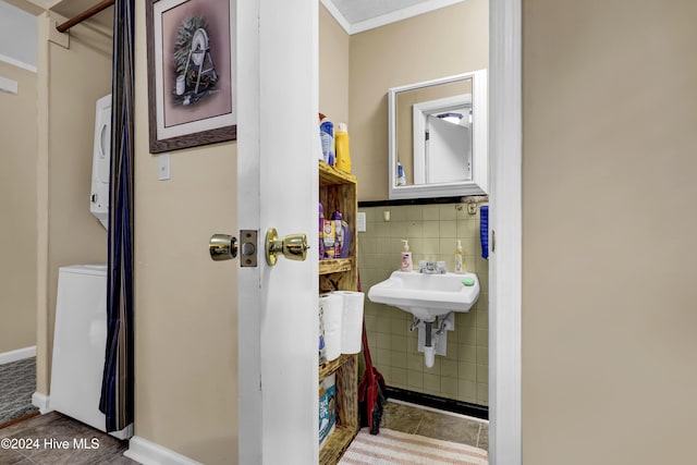 bathroom with tile patterned flooring, a sink, tile walls, and stacked washer / drying machine