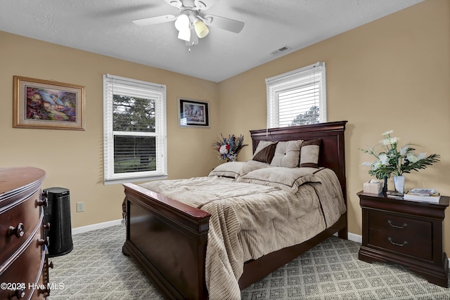 bedroom featuring a textured ceiling, light carpet, a ceiling fan, visible vents, and baseboards