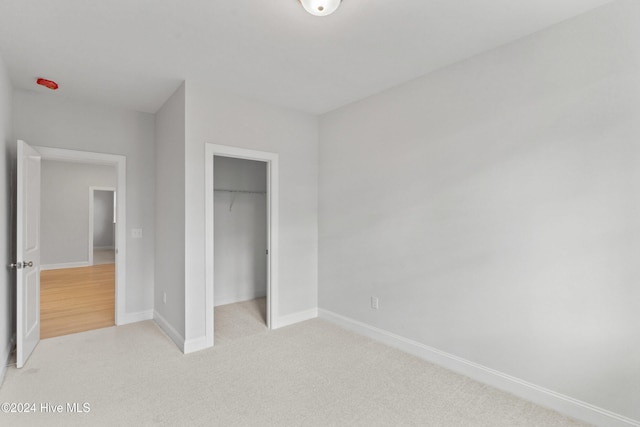 unfurnished bedroom with light carpet and a closet