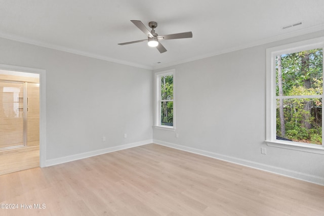 empty room featuring a healthy amount of sunlight, ornamental molding, and light hardwood / wood-style flooring