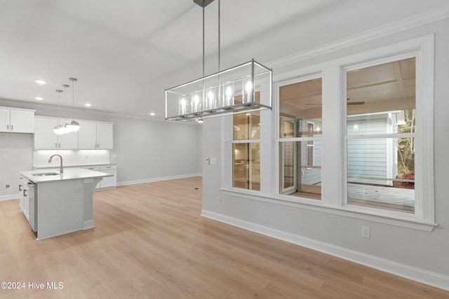 kitchen featuring a kitchen island with sink, white cabinets, decorative light fixtures, and light wood-type flooring