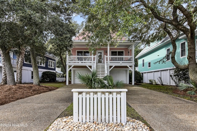 221 Seawatch Way, Kure Beach, NC 28449 - coastal home featuring driveway, a garage, stairs, and covered porch