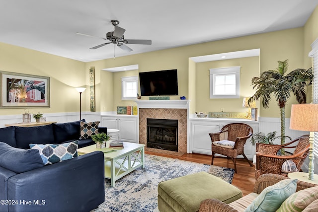 221 Seawatch Way, Kure Beach, NC 28449 - living room featuring ceiling fan, a tiled fireplace, wainscoting, and light wood-style floors