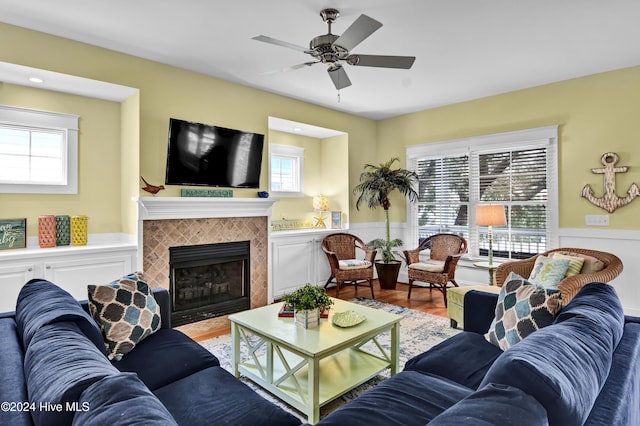 221 Seawatch Way, Kure Beach, NC 28449 - living area featuring healthy amount of natural light, a wainscoted wall, a ceiling fan, a tiled fireplace, and wood finished floors