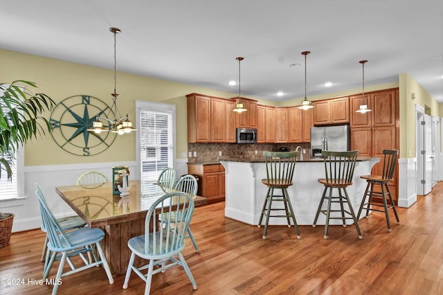 221 Seawatch Way, Kure Beach, NC 28449 - kitchen featuring appliances with stainless steel finishes, dark countertops, light wood-type flooring, a center island with sink, and a wainscoted wall