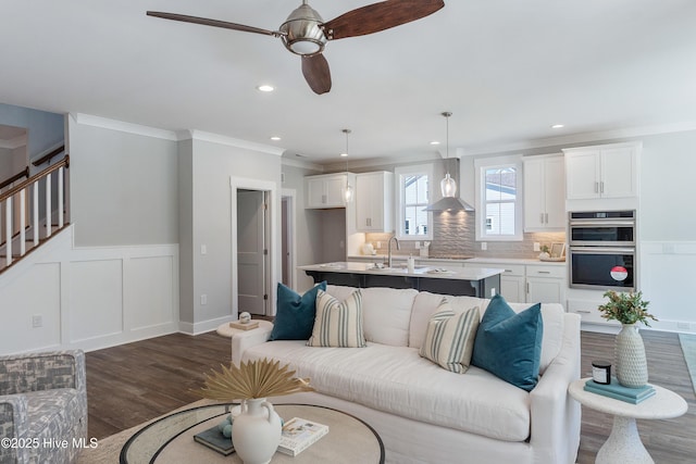 513 Moss Lake Ln, Holly Ridge, NC 28445 - living area with crown molding, ceiling fan, a wainscoted wall, stairs, and dark wood-type flooring