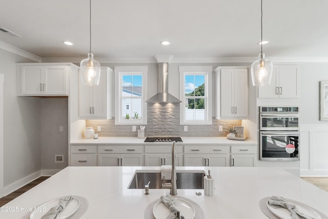 513 Moss Lake Ln, Holly Ridge, NC 28445 - kitchen featuring a sink, light countertops, wall chimney exhaust hood, white cabinetry, and visible vents