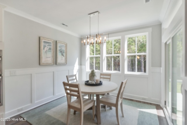 513 Moss Lake Ln, Holly Ridge, NC 28445 - dining space with a chandelier, wainscoting, a healthy amount of sunlight, and a decorative wall