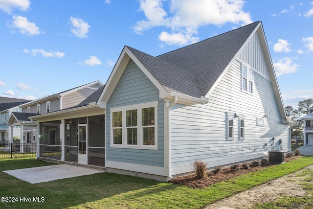 513 Moss Lake Ln, Holly Ridge, NC 28445 - rear view of property featuring roof with shingles, central AC unit, a sunroom, a yard, and a patio