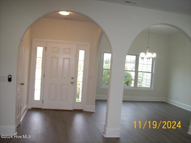 foyer featuring a chandelier, dark wood-type flooring, and a healthy amount of sunlight