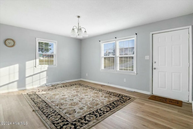 foyer entrance featuring a wealth of natural light, light hardwood / wood-style floors, and a notable chandelier