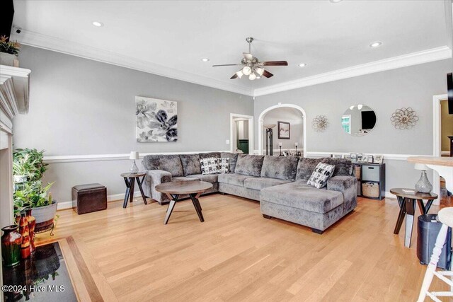 living room with light wood-type flooring, ceiling fan, and crown molding