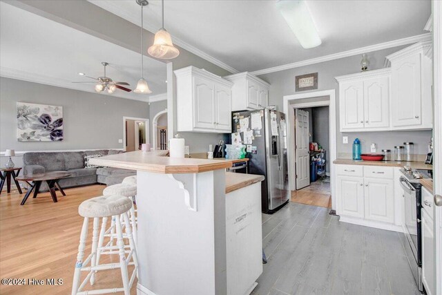 kitchen with stainless steel appliances, white cabinetry, a breakfast bar area, and light hardwood / wood-style flooring