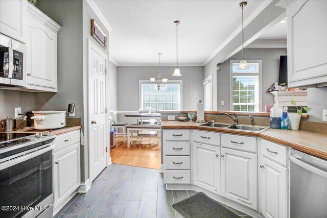 kitchen with sink, stainless steel appliances, decorative light fixtures, white cabinets, and light wood-type flooring