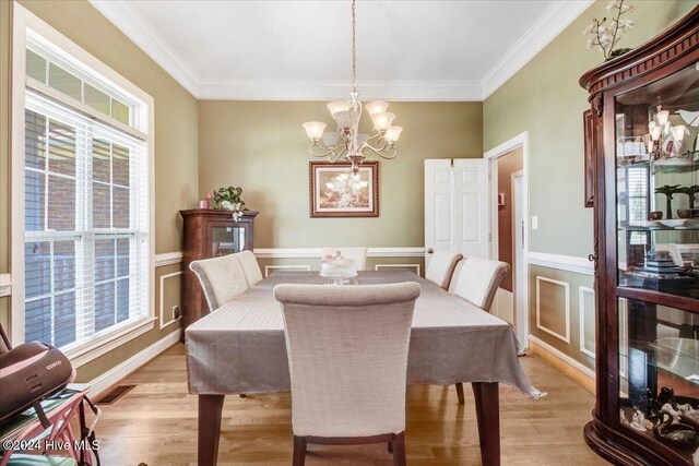 dining space with light wood-type flooring, a wealth of natural light, and ornamental molding