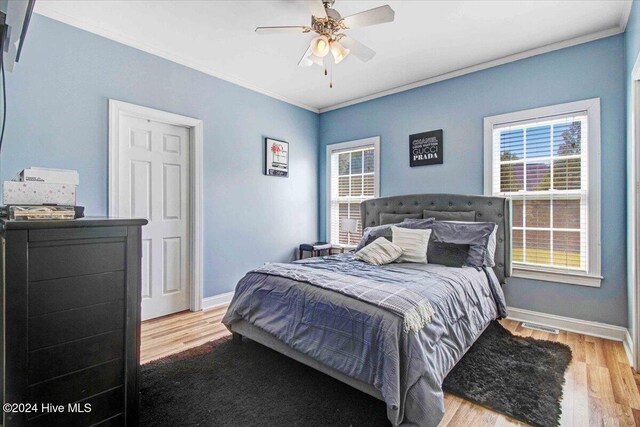 bedroom with light hardwood / wood-style flooring, ceiling fan, and crown molding