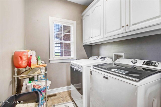 laundry area with washing machine and dryer, cabinets, and light hardwood / wood-style floors