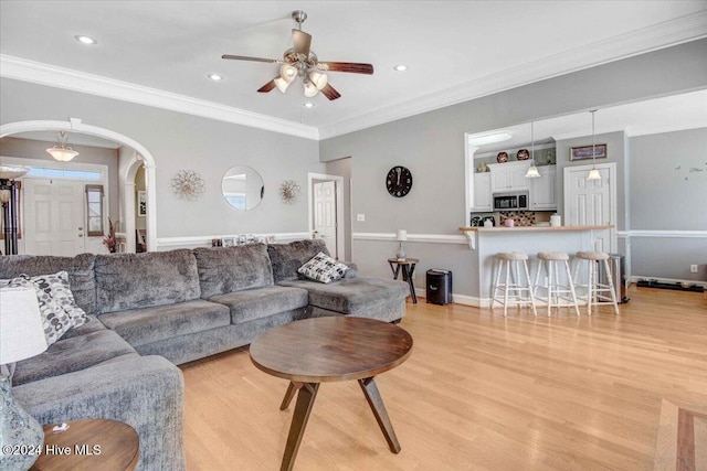 living room featuring ceiling fan, light hardwood / wood-style floors, and ornamental molding