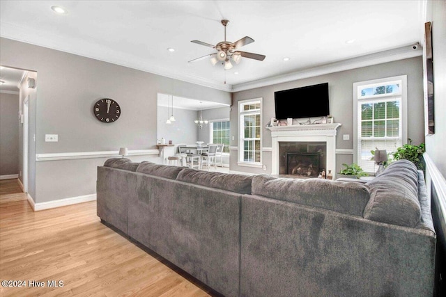 living room featuring light hardwood / wood-style flooring, ceiling fan with notable chandelier, and ornamental molding