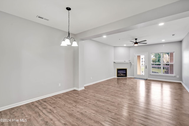 unfurnished living room with ceiling fan with notable chandelier and hardwood / wood-style flooring